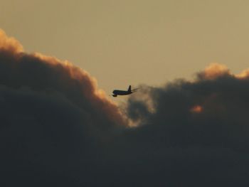 Low angle view of silhouette airplane flying against sky