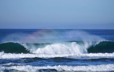 Scenic view of sea against rainbow waves clear sky