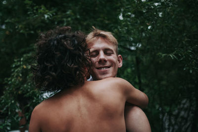 Portrait of smiling young man against trees