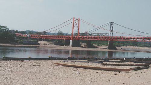 Suspension bridge over river against clear sky