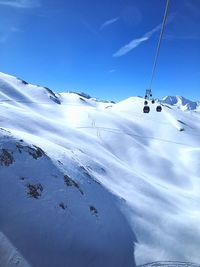 Low angle view of snow covered landscape against blue sky