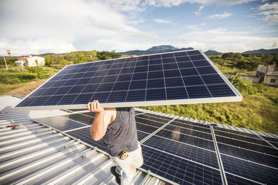 Man carries solar panel over his head during installation.