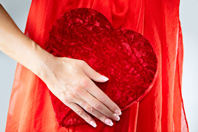 Close-up of woman hand holding red leaf against white background