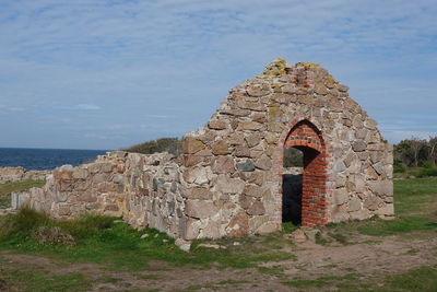 Old ruin building by sea against sky