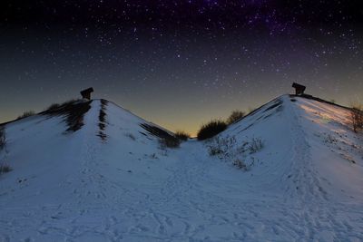 Snow covered landscape against sky at night