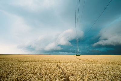 Scenic view of electricity pylon on field against sky