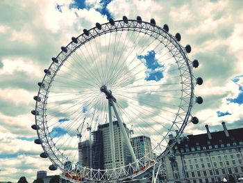 Low angle view of ferris wheel against cloudy sky