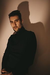 Portrait of young man standing against wall