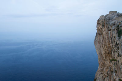 Scenic view of sea and rocks against blue sky