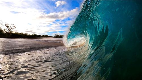 Sea waves rushing on shore against sky