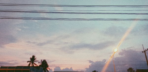 Low angle view of electricity pylon against sky during sunset