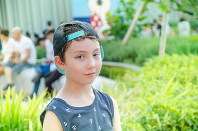 Portrait of boy wearing baseball cap by plants at park