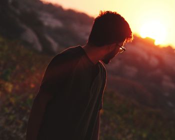 Side view of young man looking at sunset