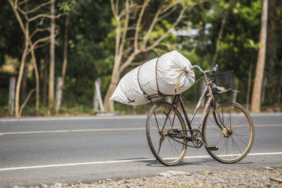 Sack tied to bicycle parked on road