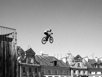 Low angle view of man cycling against clear sky