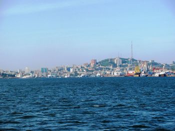 Sea by buildings in city against sky