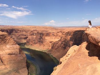 Woman relaxing at horseshoe bend against sky