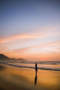 Silhouette man on beach against sky during sunset