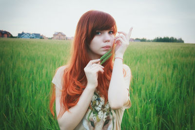 Portrait of young woman standing on field against sky