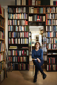 Portrait of confident owner sitting on chair in antique book shop