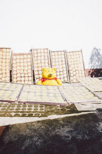 Yellow toy on wall against clear sky