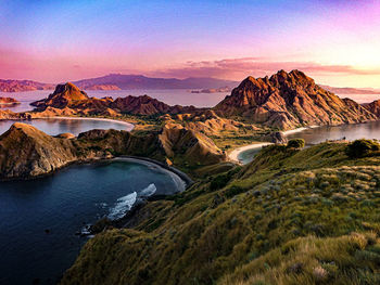 Scenic view of river by mountains against sky during sunset