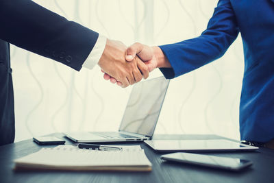 Cropped image of businessmen shaking hands at table