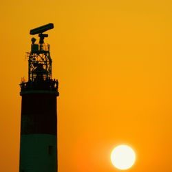 Silhouette of lighthouse against orange sky