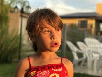 Cute thoughtful girl looking away in lawn during sunset