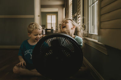 Children sitting in front of fan
