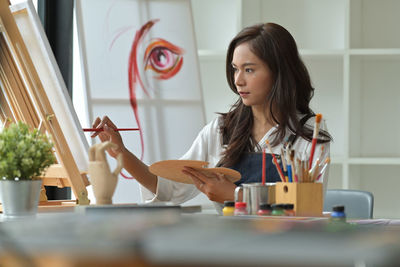 Portrait of young woman sitting on table at home