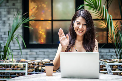Young woman using smart phone while sitting in laptop