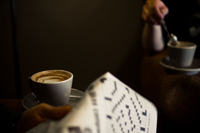 Close-up of hand holding coffee cup on table