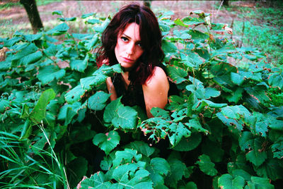 Portrait of young woman sitting amidst plants