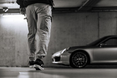 Low section of man walking towards sports car in parking lot