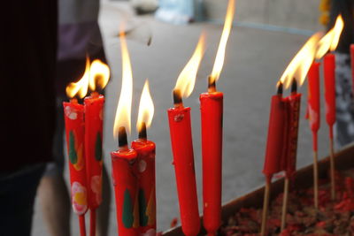Close-up of burning candles in temple against building