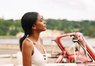 Contemplating young woman looking away while standing against boat