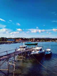 Boats moored at harbor against sky