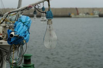 Close-up of fishing net hanging on rope against sky