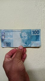 Close-up of hand holding text against wall