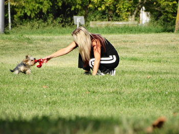 Young woman playing with dog on field