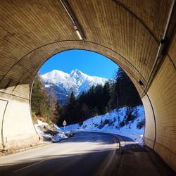 Empty road in tunnel against snow covered mountain