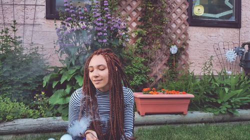 Young woman with braided hair sitting in yard