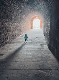 Rear view of man walking in tunnel