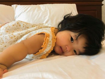 High angle portrait of cute baby girl lying on bed at home