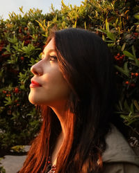 Close-up of woman looking away against plants