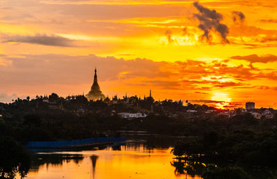 Silhouette of buildings against cloudy sky during sunset