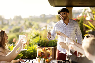 Friends with wineglasses at dining table on porch