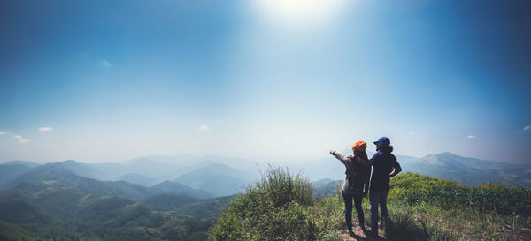 Rear view of man standing on mountain against sky