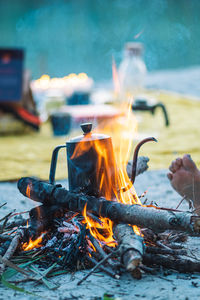 Preparing coffee or tea on an bonfire with branches and flames outdoor in the nature, vertical
